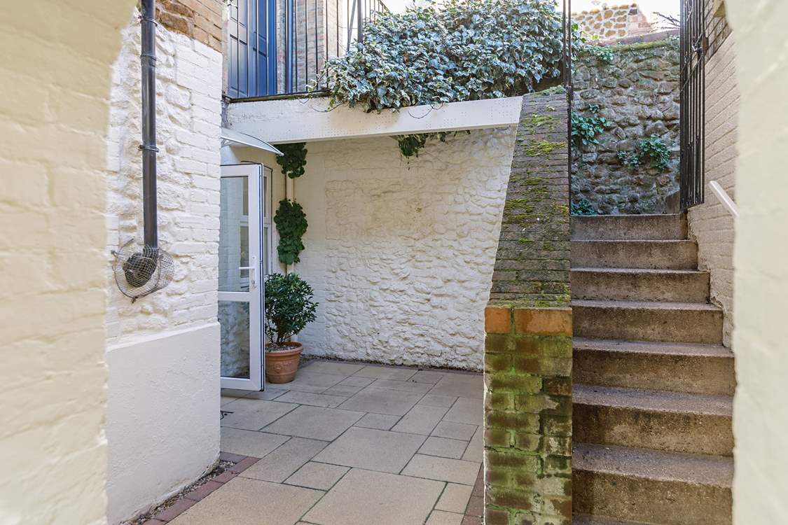 Steps lead down from the private parking area to the enclosed courtyard.