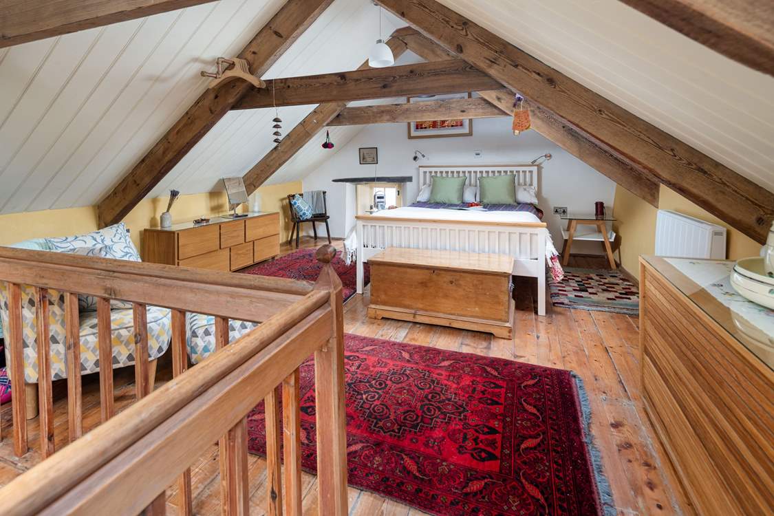 The hushed mezzanine bedroom, decked with Welsh wool blankets, overlooking Y Gegin Fawr. Watch out for the low beams.
