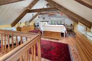 The hushed mezzanine bedroom, decked with Welsh wool blankets, overlooking Y Gegin Fawr. Watch out for the low beams.