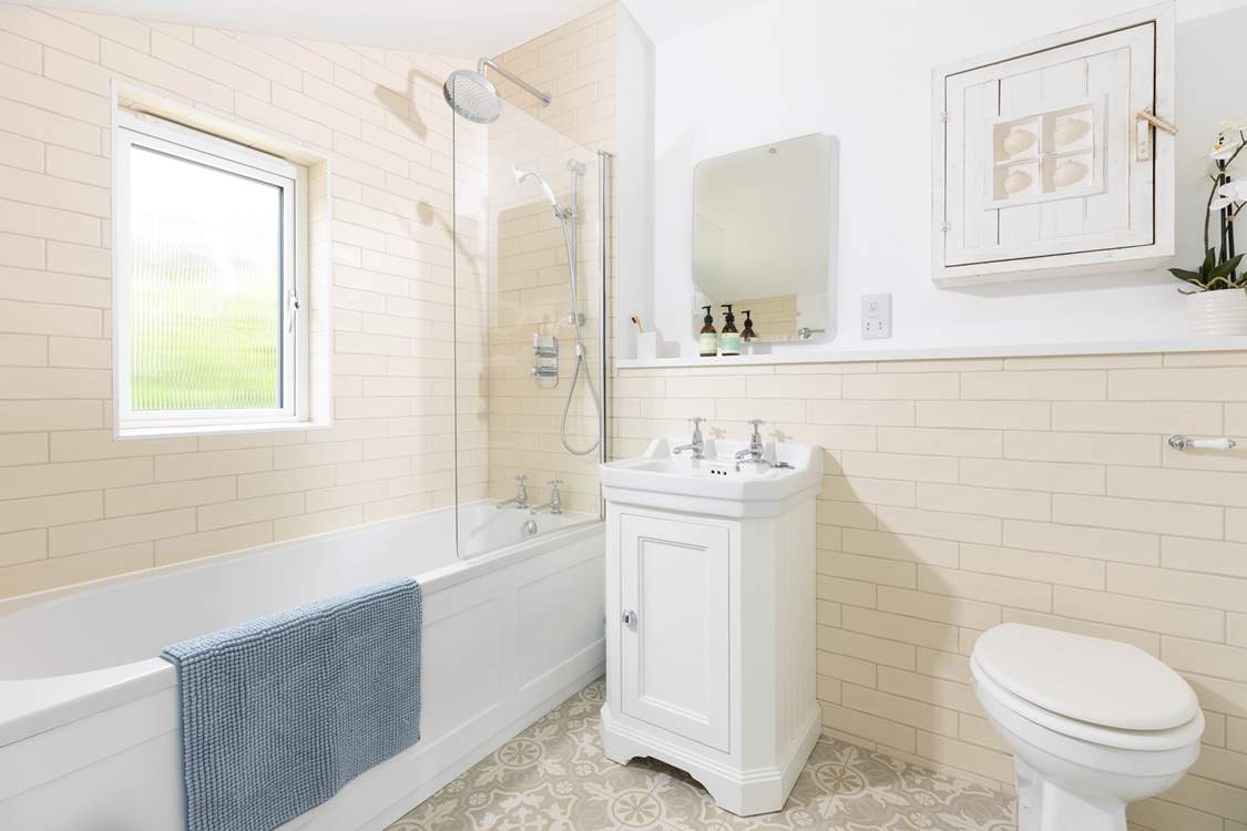 The family bathroom has a bath with a rainfall shower overhead.