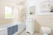 The family bathroom has a bath with a rainfall shower overhead.