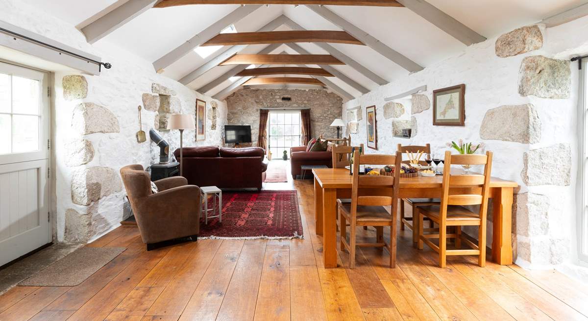 A huge open plan living space with whitewashed walls, rustic beams, a cosy wood-burner and floor to ceiling traditional windows awaits.