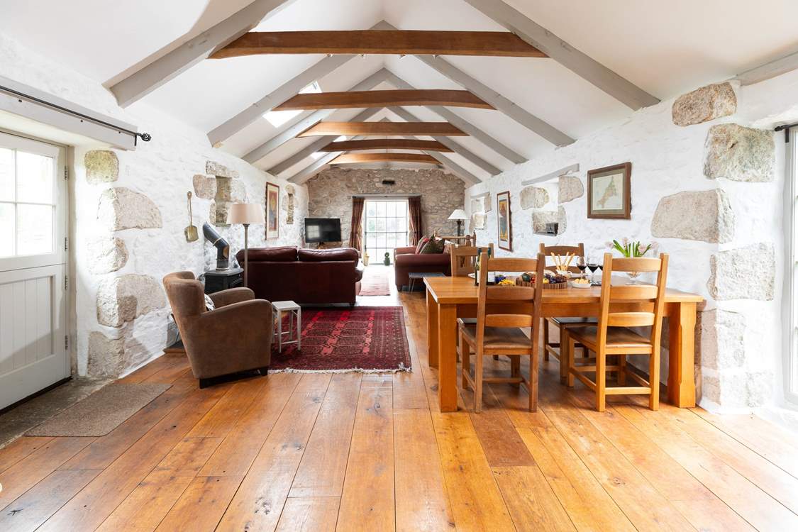A huge open plan living space with whitewashed walls, rustic beams, a cosy wood-burner and floor to ceiling traditional windows awaits.