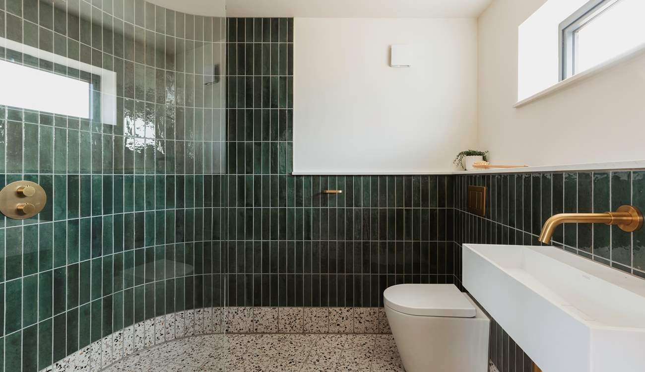 Emerald green tiles and splashes of gold give the shower room a spa-like feel.