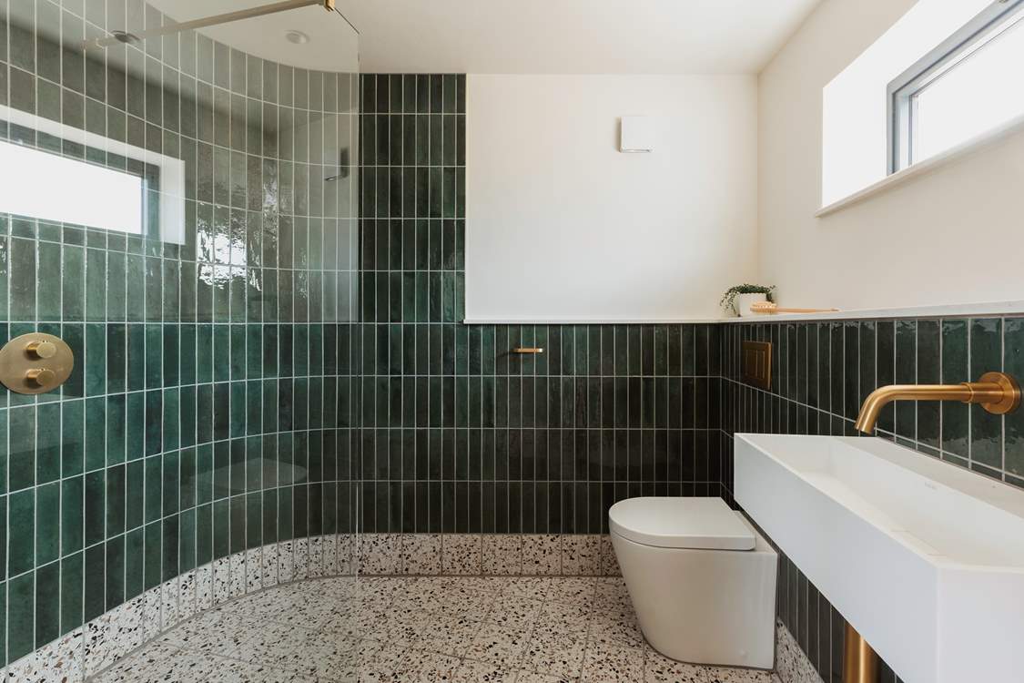 Emerald green tiles and splashes of gold give the shower room a spa-like feel.