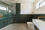 Emerald green tiles and splashes of gold give the shower room a spa-like feel.
