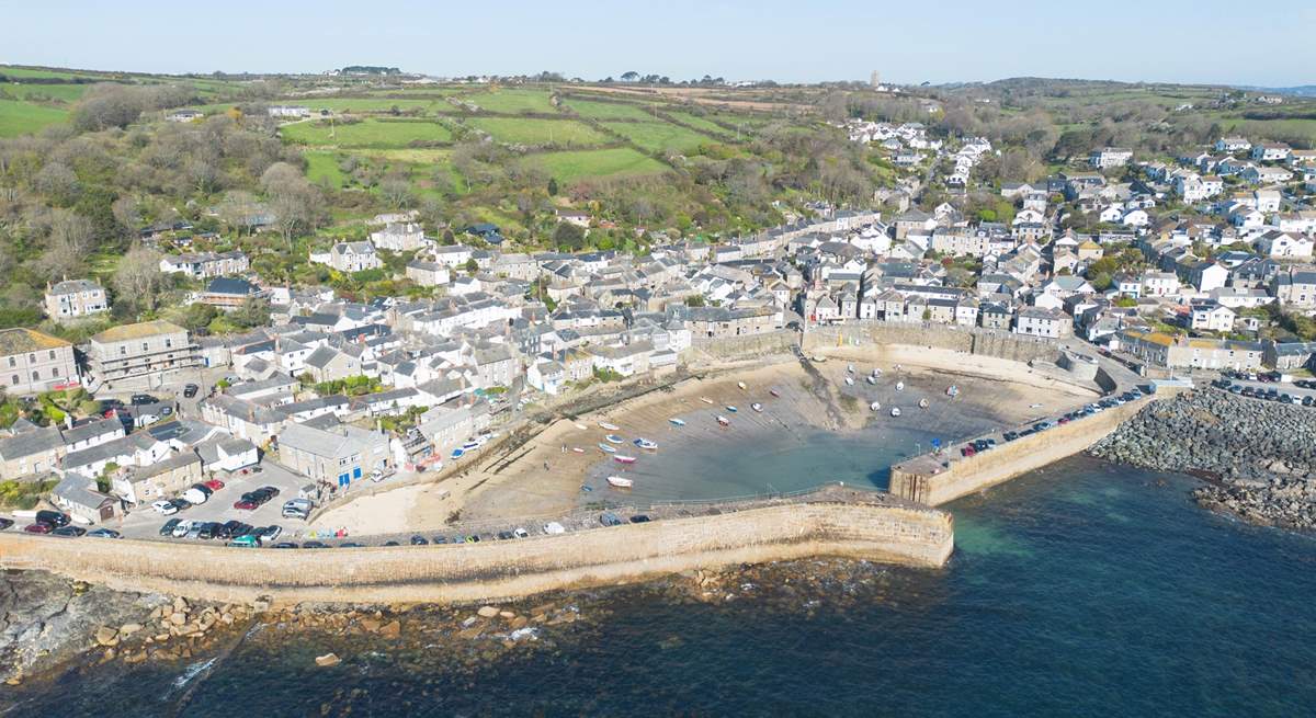 An aerial view of this small historic coastal village, with its sandy beach, bobbing fishing boats and many tales of smugglers gone by.
