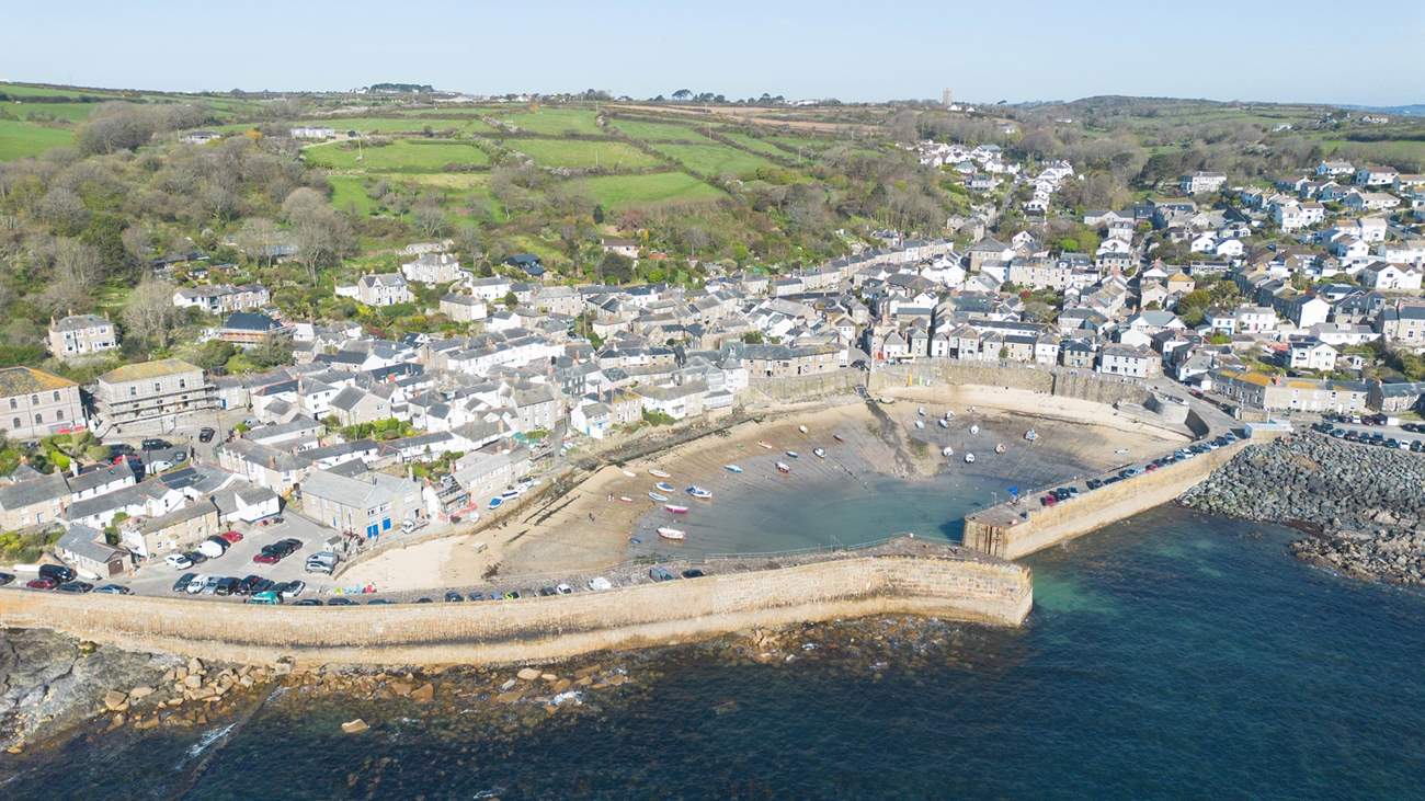 An aerial view of this small historic coastal village, with its sandy beach, bobbing fishing boats and many tales of smugglers gone by.