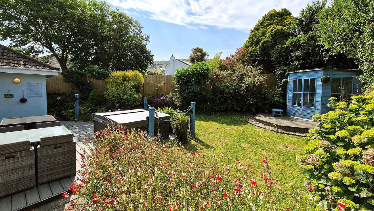 The tranquil garden is surrounded by trees and mature shrubs.