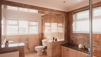 Bedroom 1's stylish en suit has a corner bath...