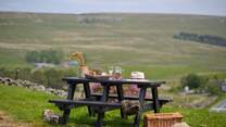 The garden table sits atop the garden and looks over the fields and hills. 