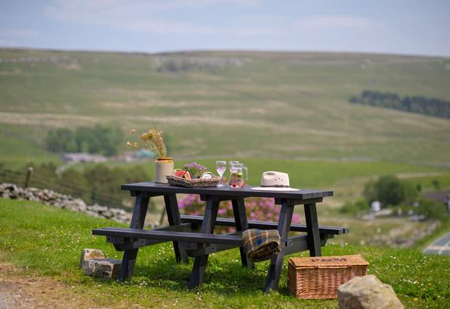 The garden table sits atop the garden and looks over the fields and hills. 