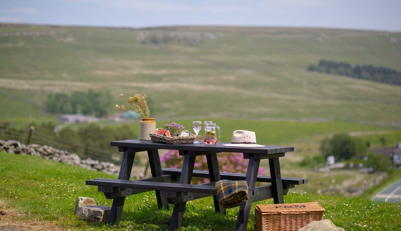 The garden table sits atop the garden and looks over the fields and hills. 