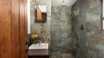 Refresh in the luxe bathroom with a waterfall shower, sink and WC.