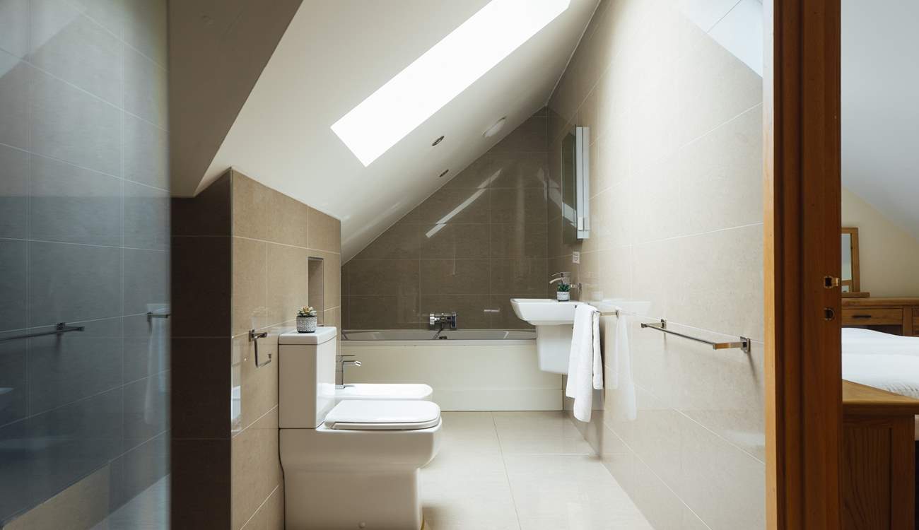 Exquisite bathroom with rainfall option shower and bath tub. Doors leading to the principal and twin bedrooms. 