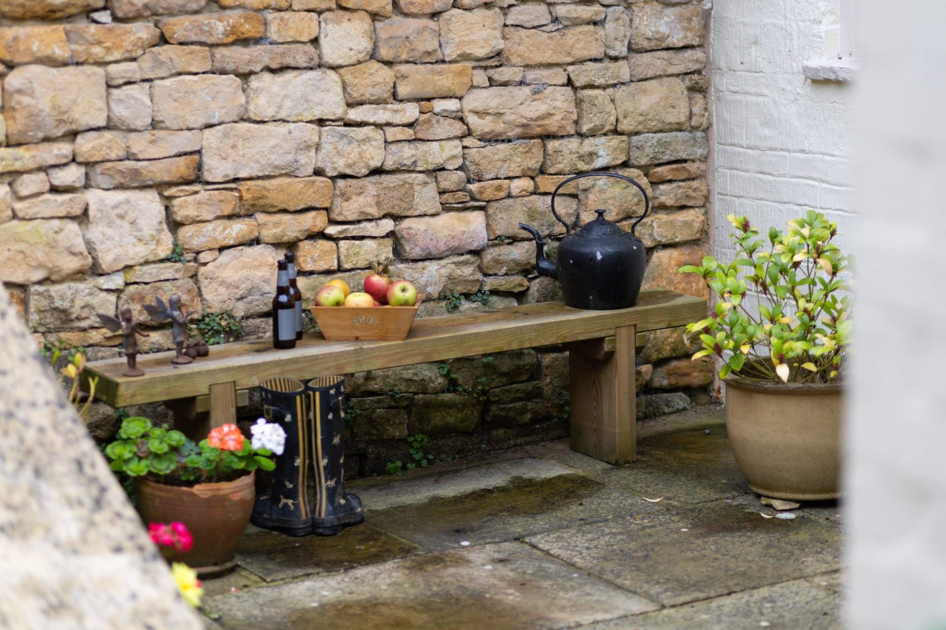 Cotswold stone forms a backdrop to the seating in front of this pretty cottage. 