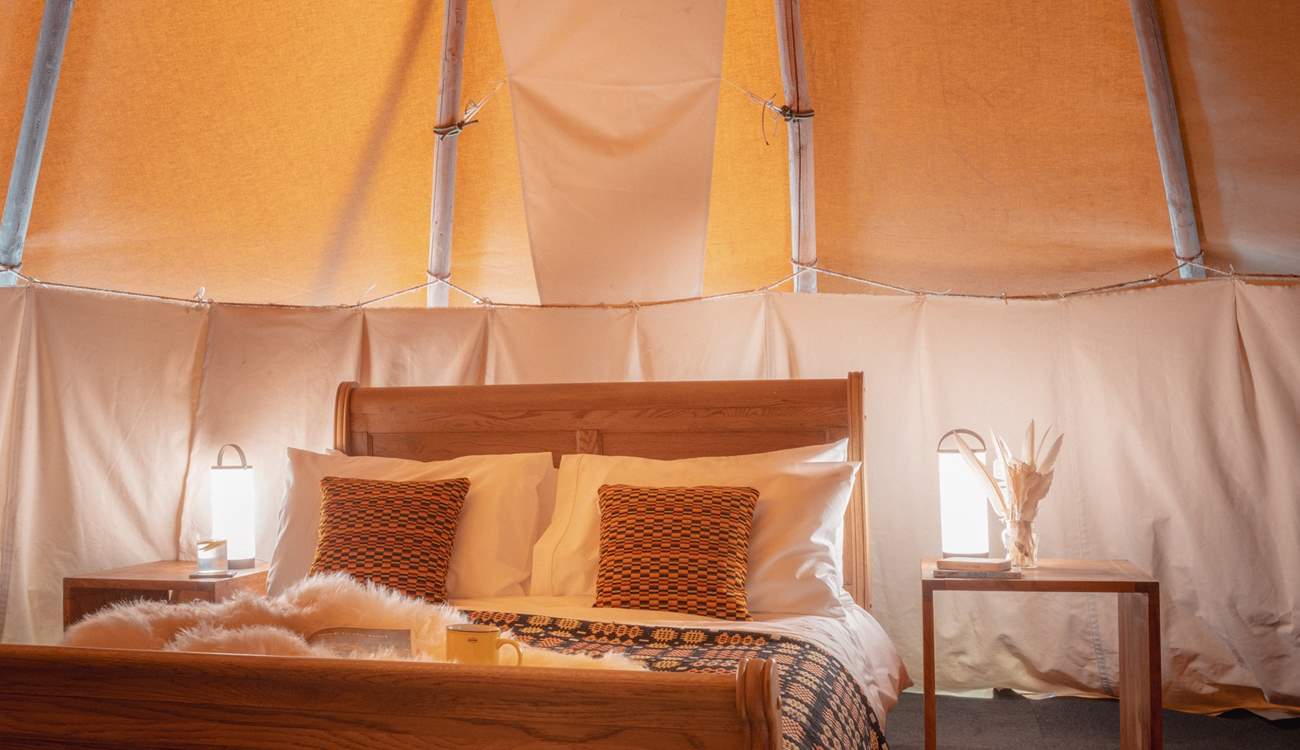 The comfy double bed is adorned with cushions and throws for ultimate relaxation.