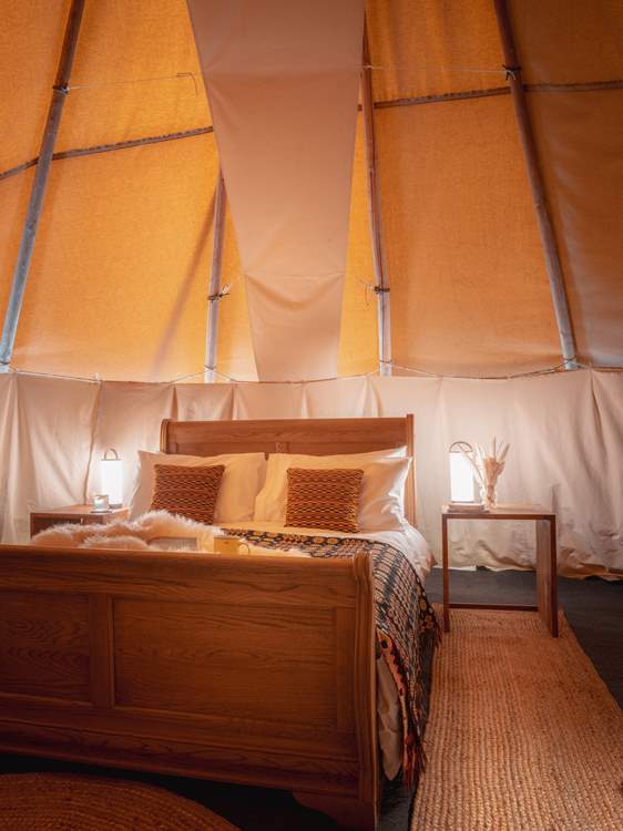 The comfy double bed is adorned with cushions and throws for ultimate relaxation.