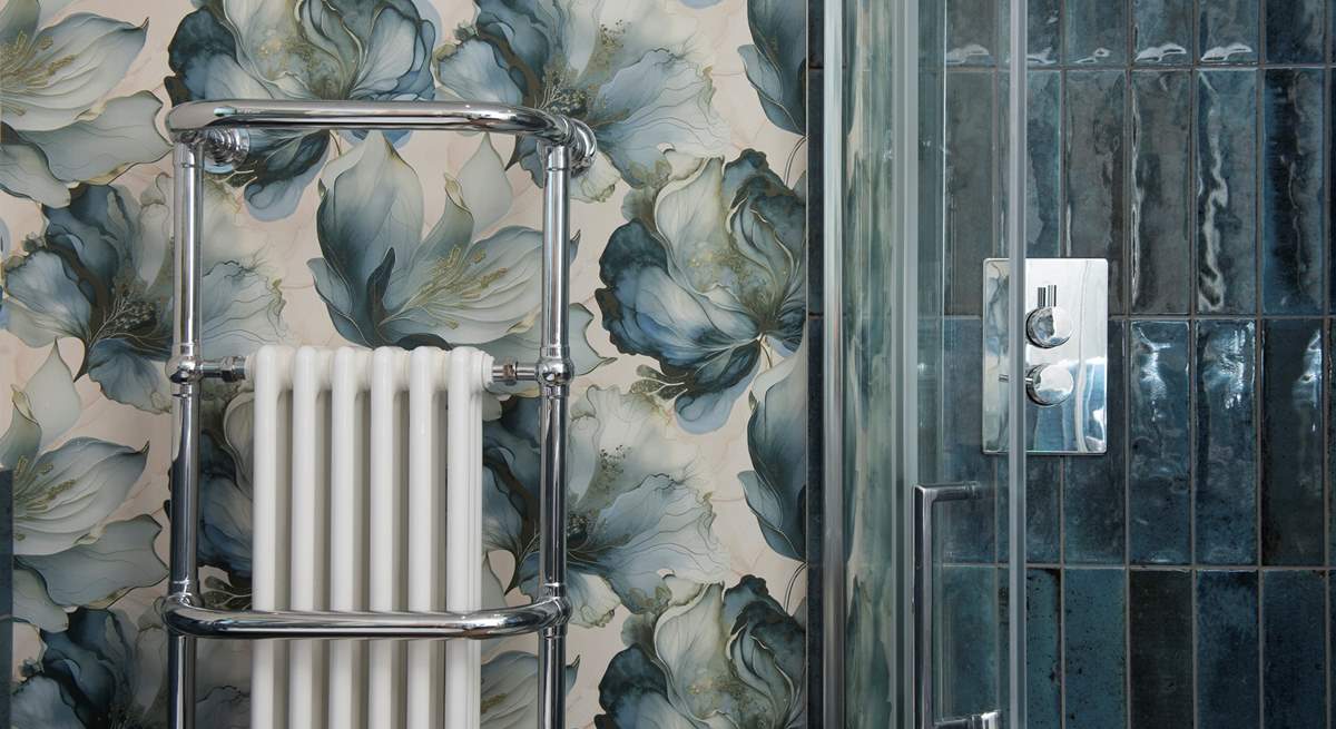 Relax in style with the striking blue tiles, designer wallpaper and a huge heated towel rail.