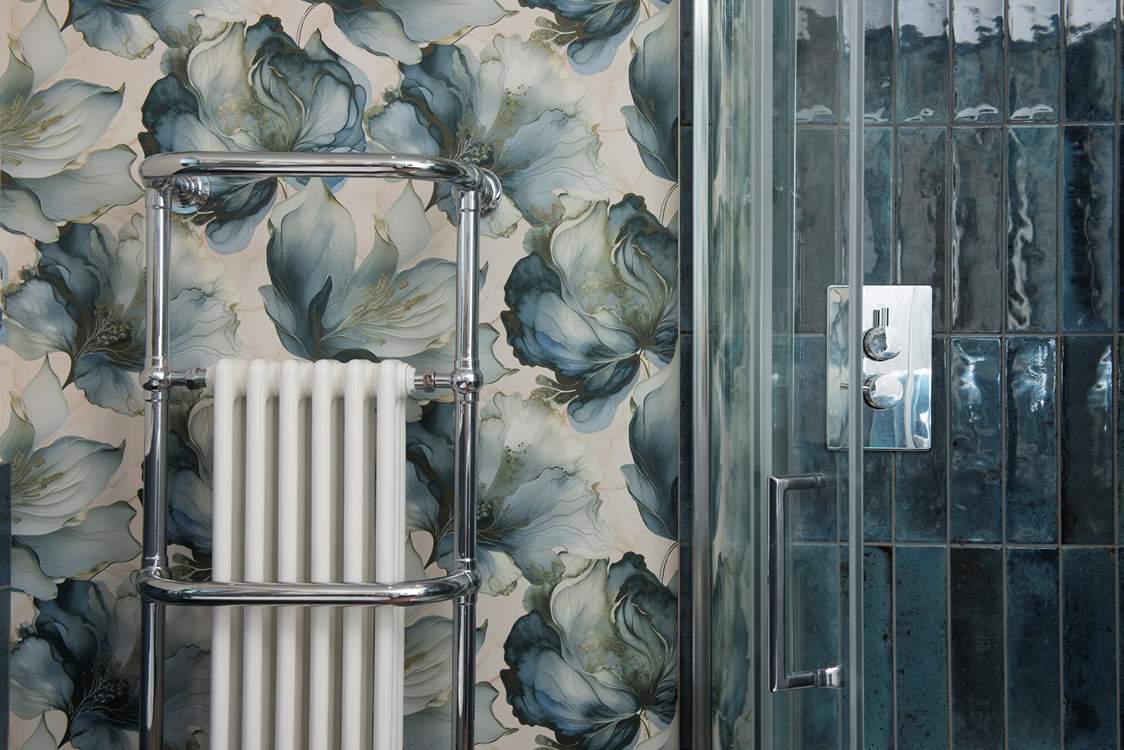 Relax in style with the striking blue tiles, designer wallpaper and a huge heated towel rail.