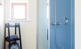 A crisp and spacious shower area styled in kingfisher blue with a rainfall showerhead to help you unwind and refresh after a day exploring. - Thumbnail Image