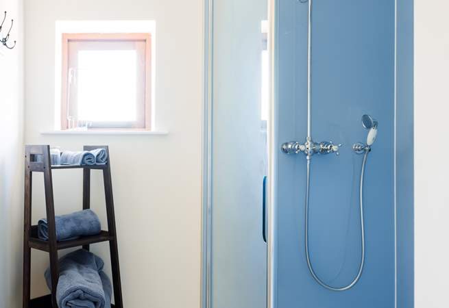 A crisp and spacious shower area styled in kingfisher blue with a rainfall showerhead to help you unwind and refresh after a day exploring.