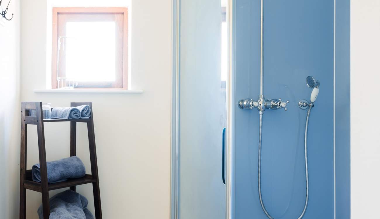 A crisp and spacious shower area styled in kingfisher blue with a rainfall showerhead to help you unwind and refresh after a day exploring.