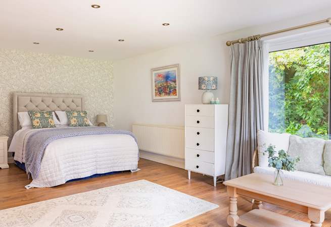 The ground floor bedroom with king-size double bed has a lounge-area and patio doors that open to a terrace and garden.