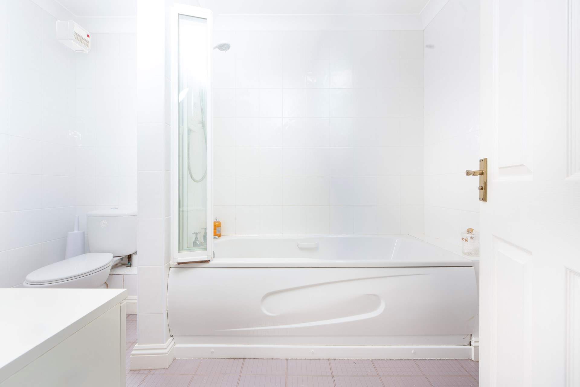 The bathroom has a bath with an overhead shower.