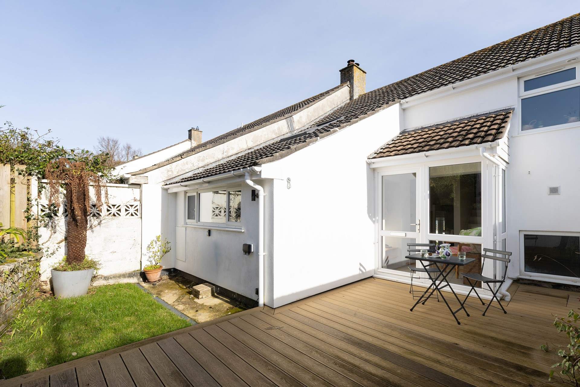 The secluded rear of the property has a bistro table and chairs. Access is from the rear where there is a medium-sized parking space and steps leading to the decked area. 