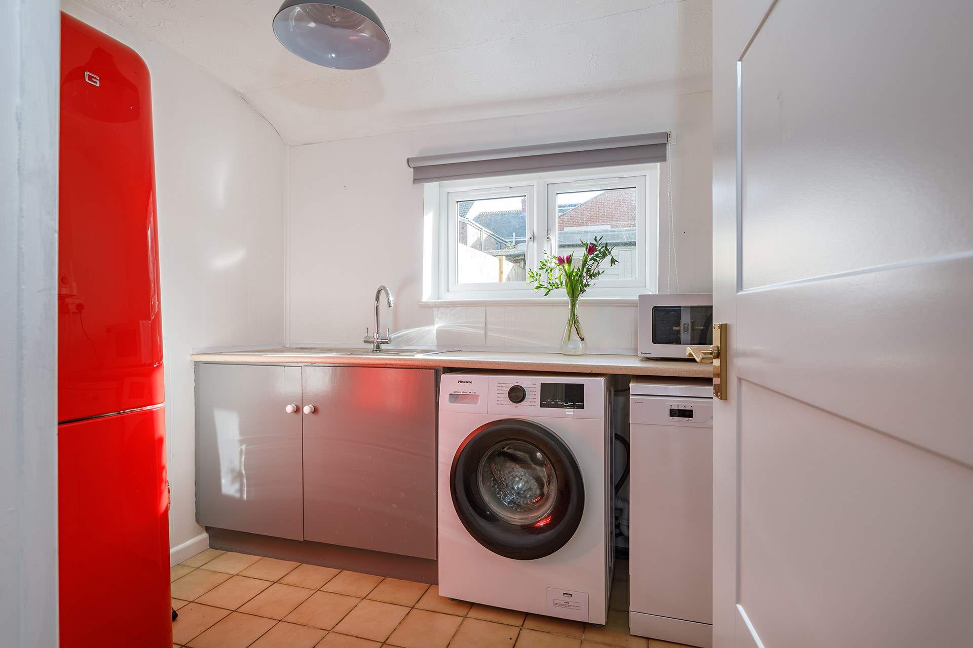 A well-appointed utility-room complete with washing machine, dishwasher and a vibrant full size fridge/freezer.