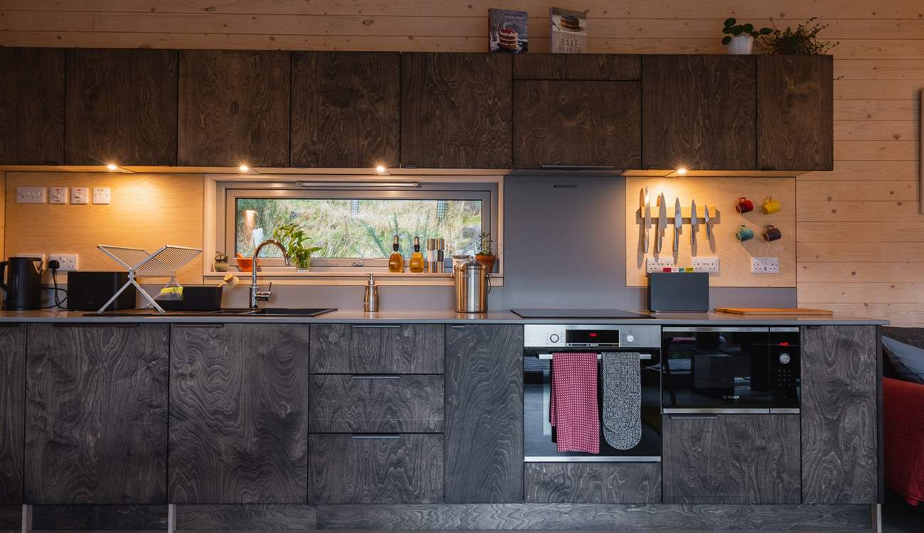 The sleek kitchen is thoughtfully equipped with everything you could need. 