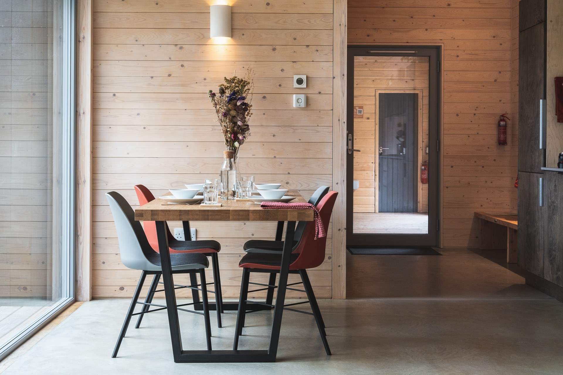 Inside, soft, neutral tones echo the woodland just beyond the glass.