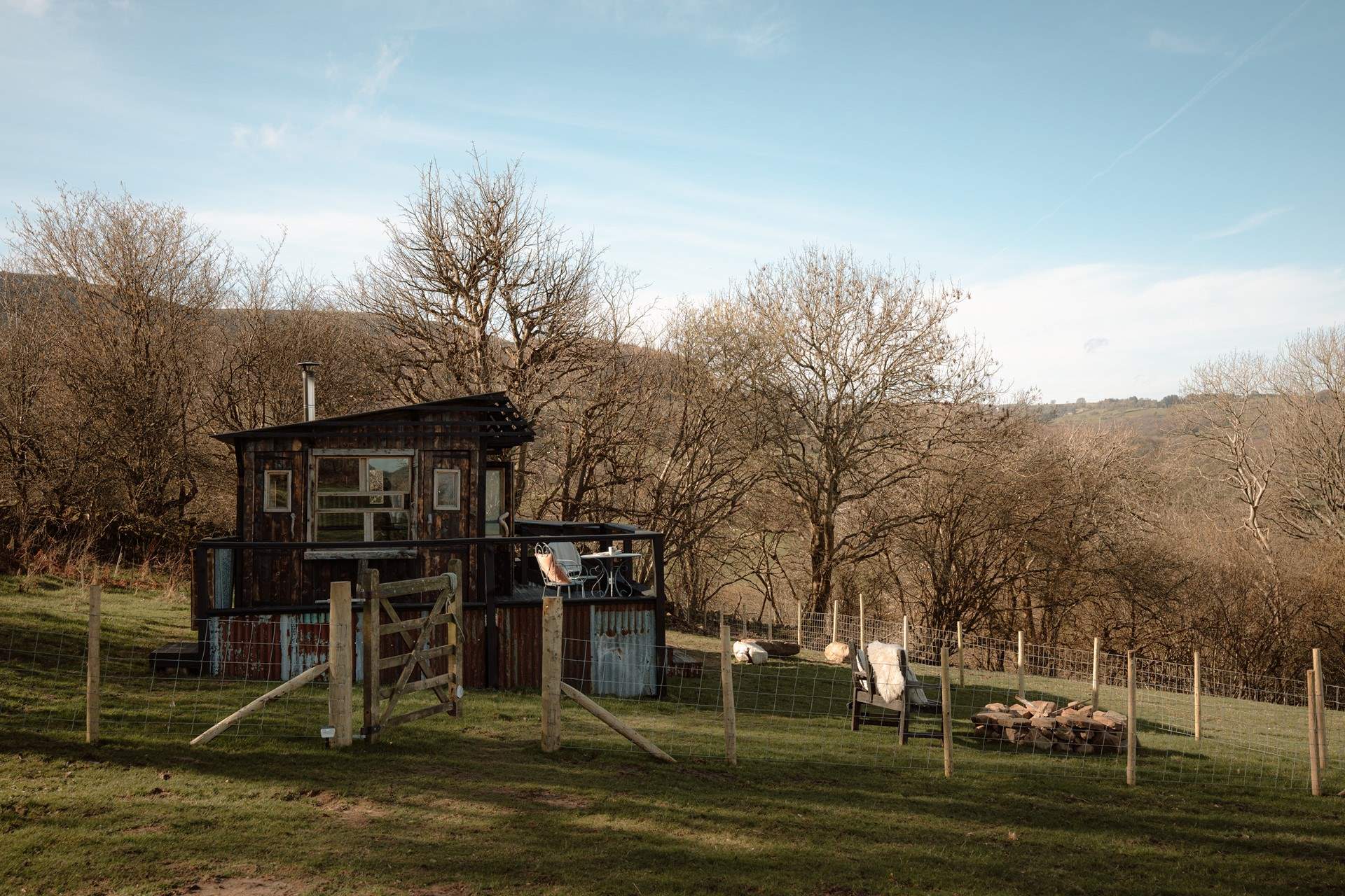 The cabin sits within its own enclosed garden, where friendly neighbouring sheep graze quietly beyond the fence.