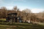 The cabin sits within its own enclosed garden, where friendly neighbouring sheep graze quietly beyond the fence.