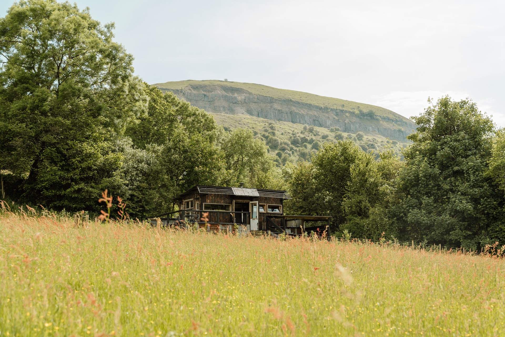 Caban Tarren - Cabin in Wales with a wood burner: Caban Tarren is a soulful, off-grid hideaway perched high on the hillside, where wide, mountain-framed views unfold in every direction. With an alfresco kitchen for balmy evenings and a flickering fire pit for watching the sun sink beyond the hills, it’s a truly special place to reconnect with nature.