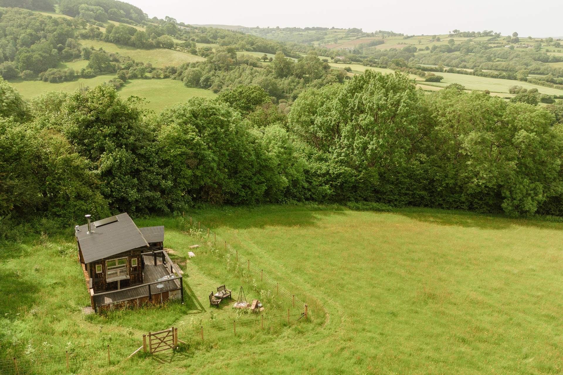 The cabin sits within its own enclosed garden, where friendly neighbouring sheep graze quietly beyond the fence.