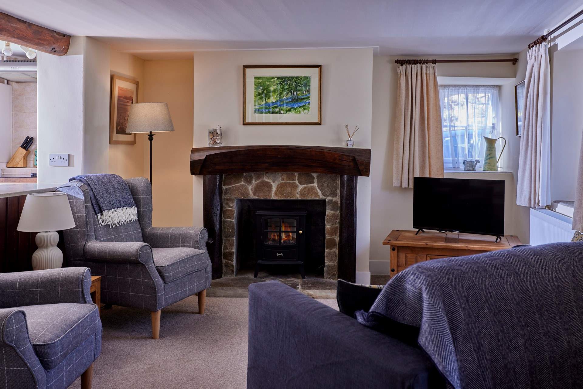 The lovely living-room is a cosy home-from-home space with lots of natural light and original features.