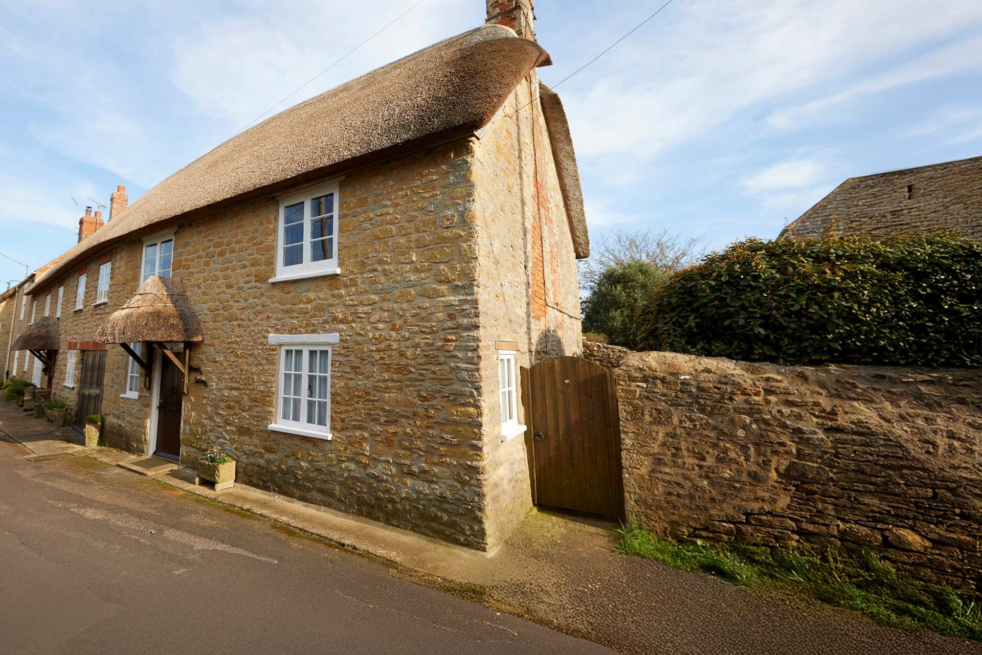 Two cars can be parked on the road just to the right of the cottage, in front of the stone wall.
