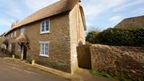 Two cars can be parked on the road just to the right of the cottage, in front of the stone wall.