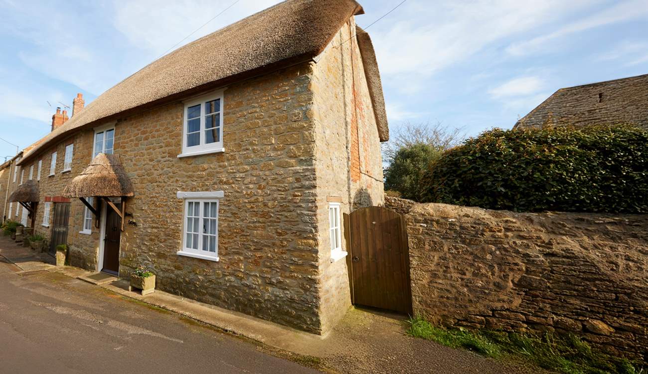 Two cars can be parked on the road just to the right of the cottage, in front of the stone wall.