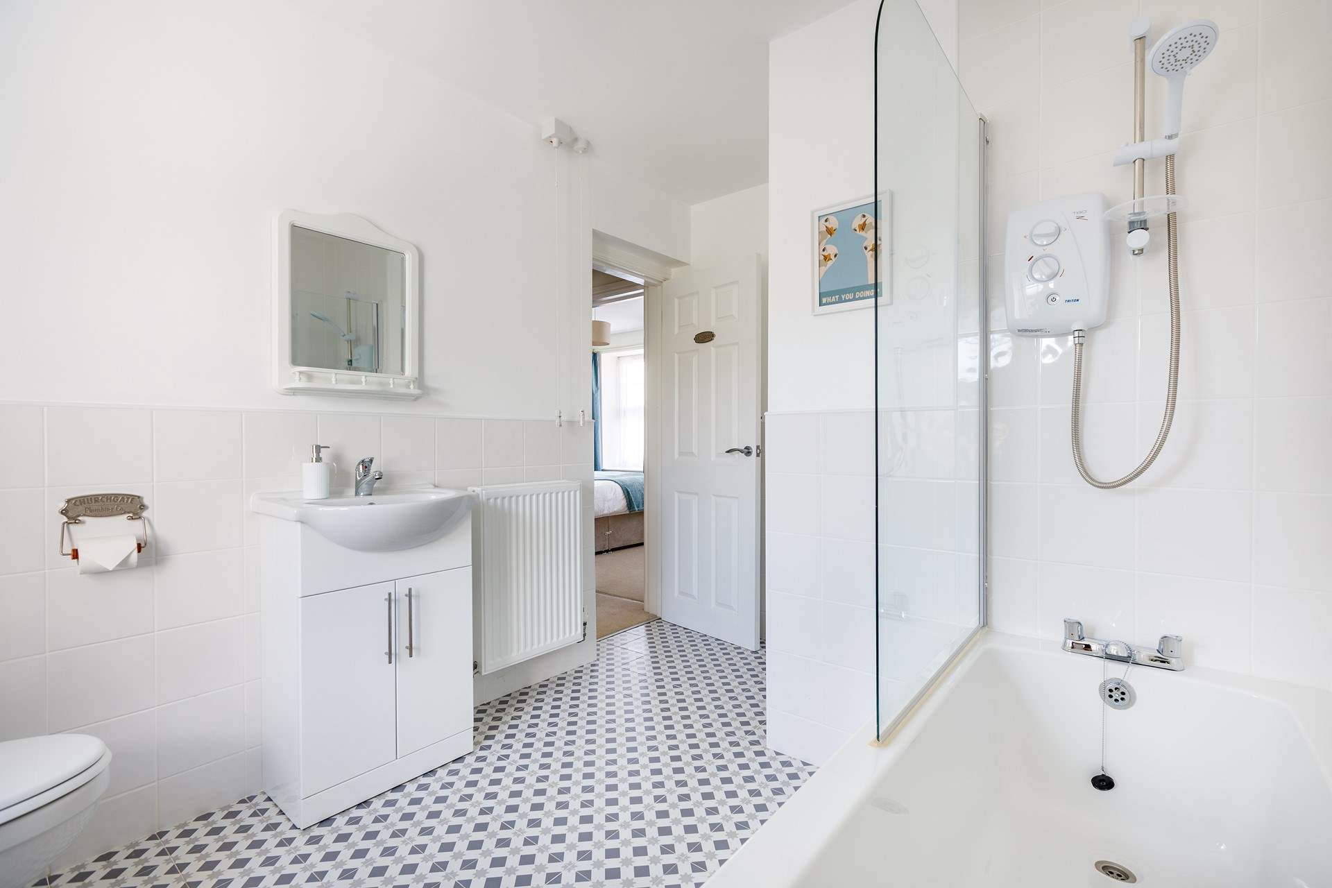This light and bright bathroom has a bath with shower over.