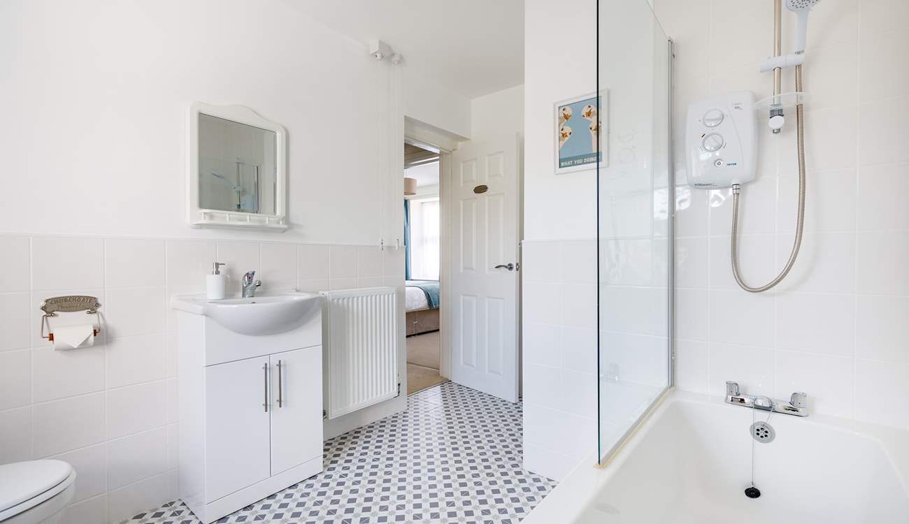 This light and bright bathroom has a bath with shower over.