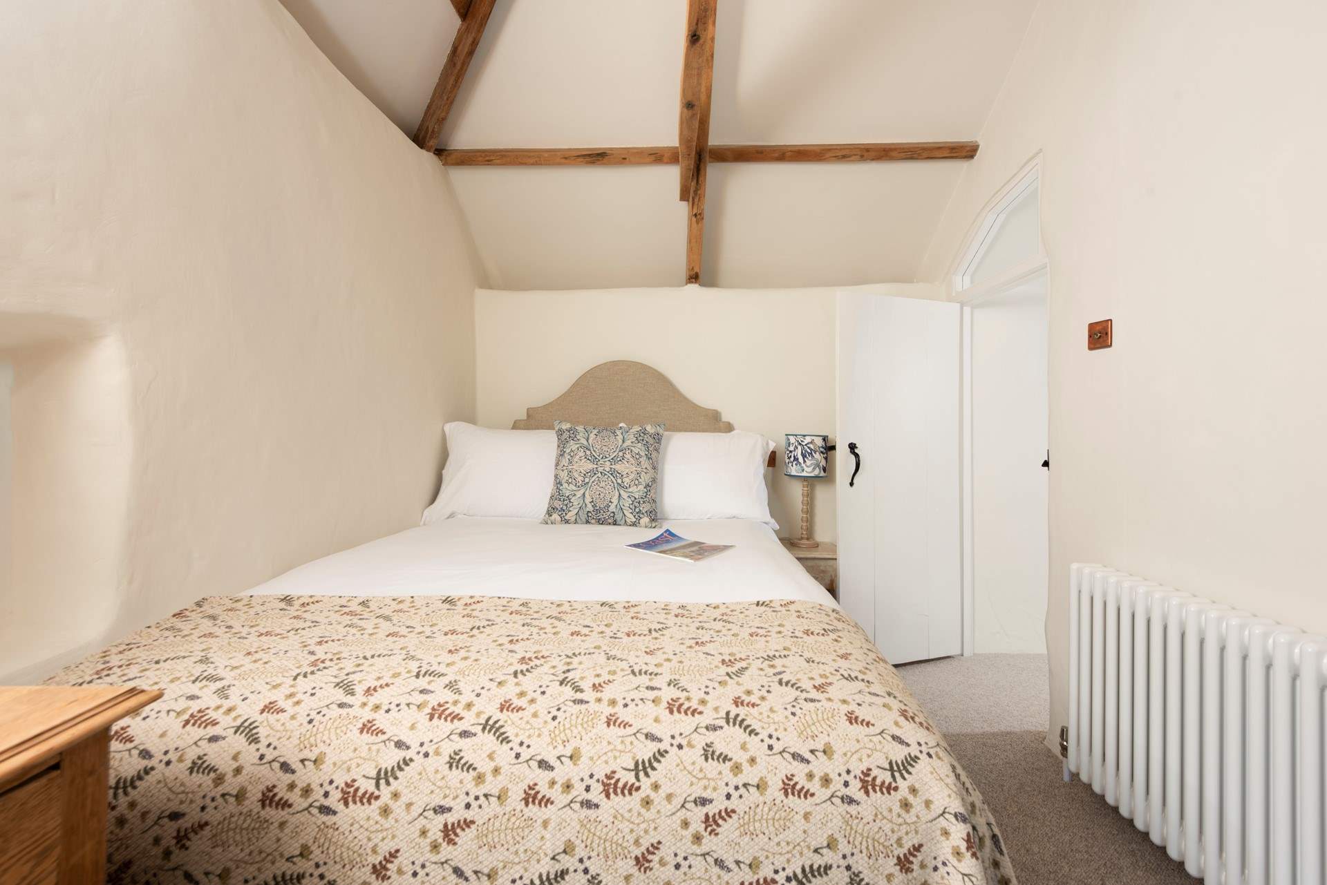 A sweet bedroom with more garden views and overhead beams.