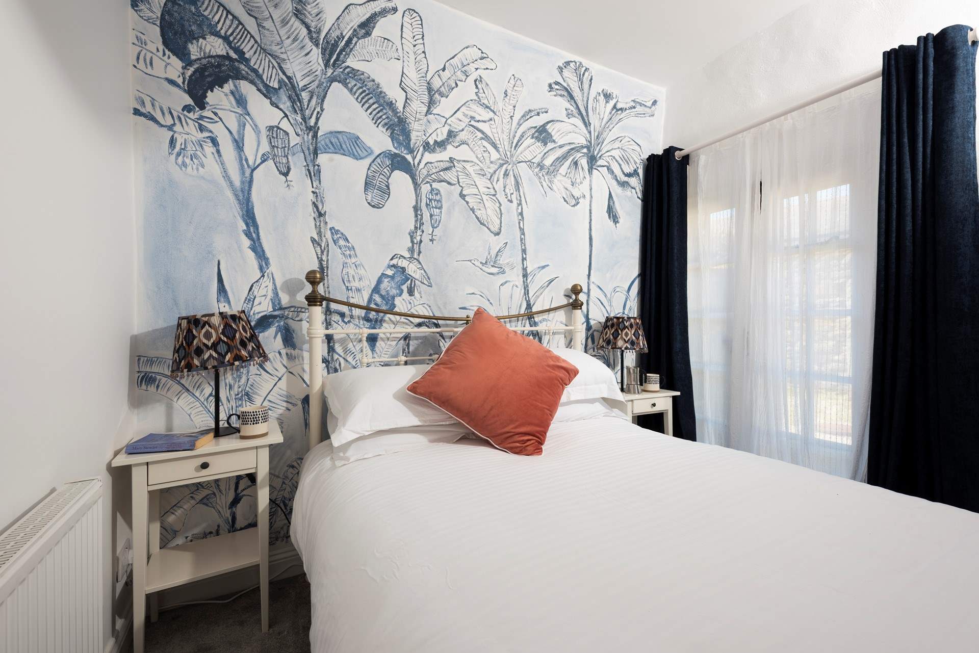 The bedroom boasts luxurious linens and a hand-painted mural.