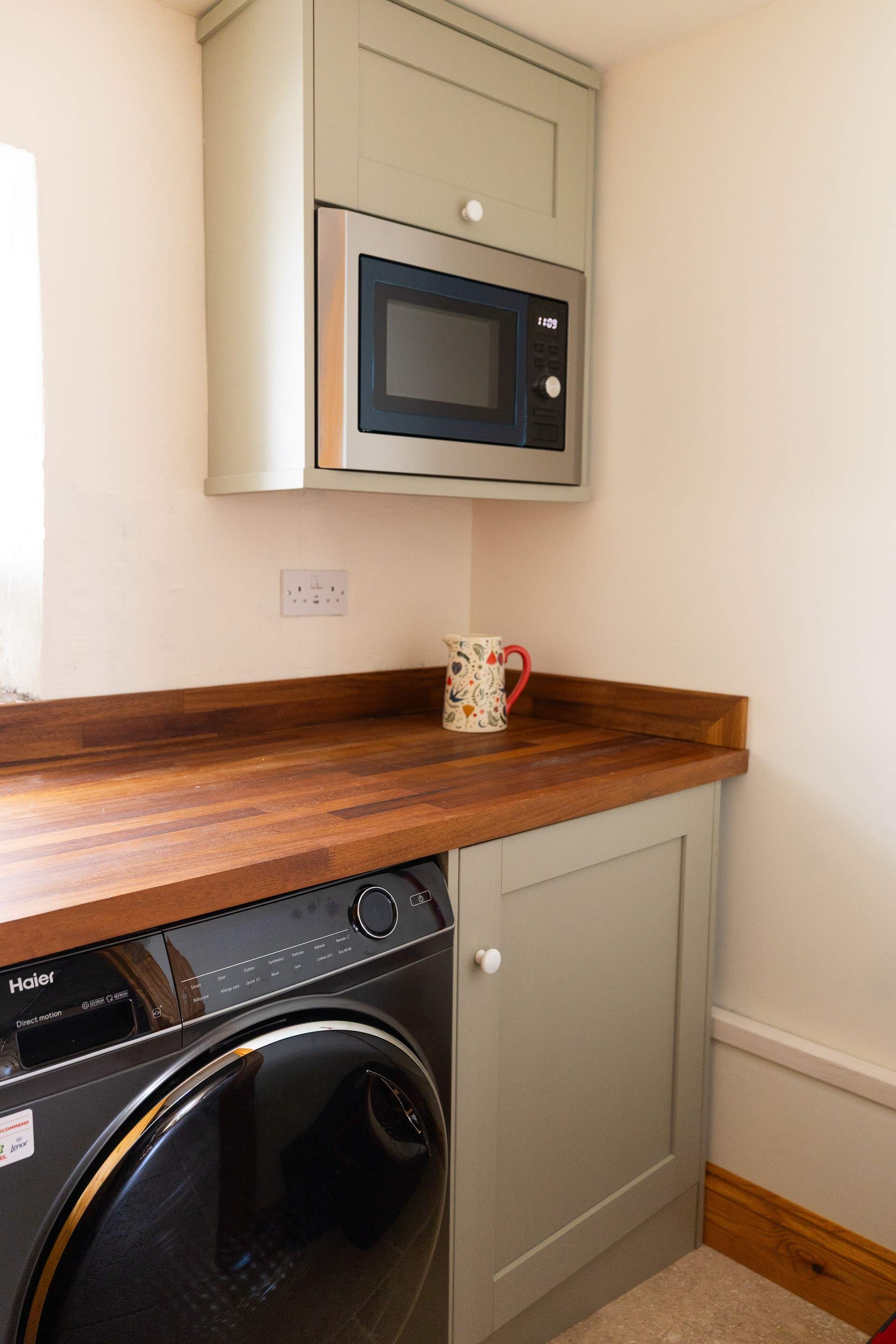 The utility-area with microwave and washing machine.