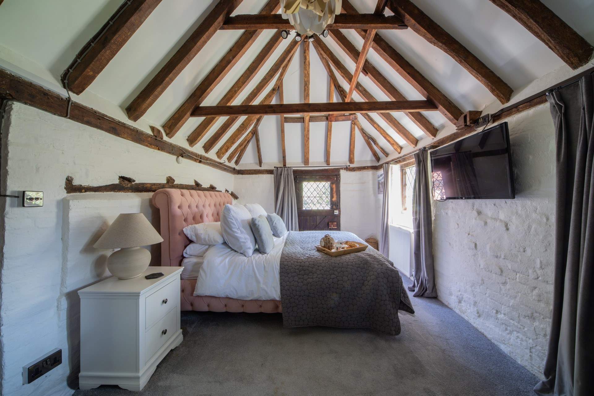 The ground floor bedroom has a beautiful pitched roof, beams and a door leading to the cottage garden.