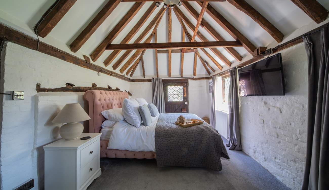 The ground floor bedroom has a beautiful pitched roof, beams and a door leading to the cottage garden.