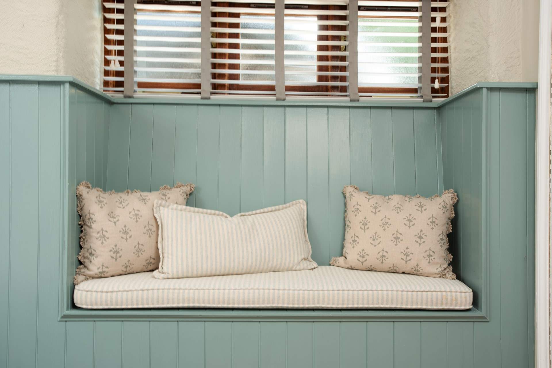 The bedroom offers this sweet place to perch adorned with pretty cushions. 