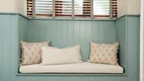 The bedroom offers this sweet place to perch adorned with pretty cushions. 